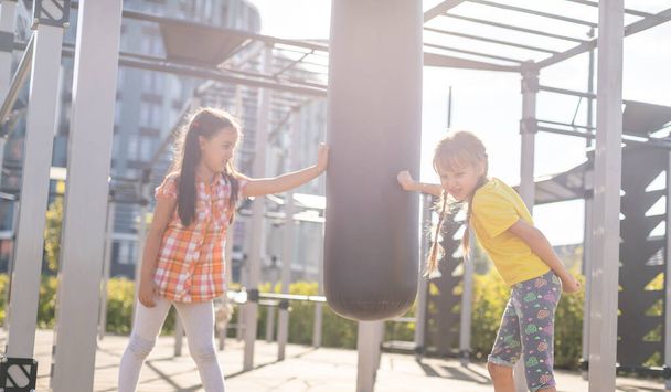 Twee schattige kleine meisjes die plezier hebben op een speeltuin in de zomer. Sportactiviteiten voor kinderen. - Foto, afbeelding