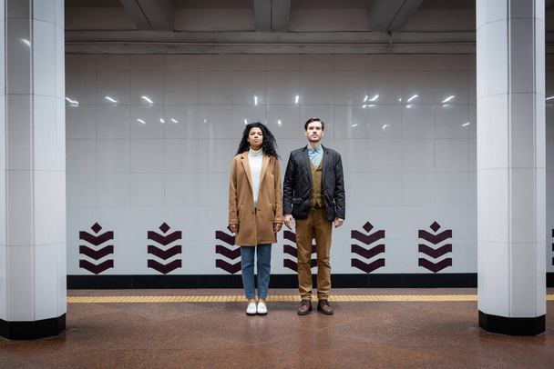 full length of african american woman and man standing in subway  - Fotó, kép
