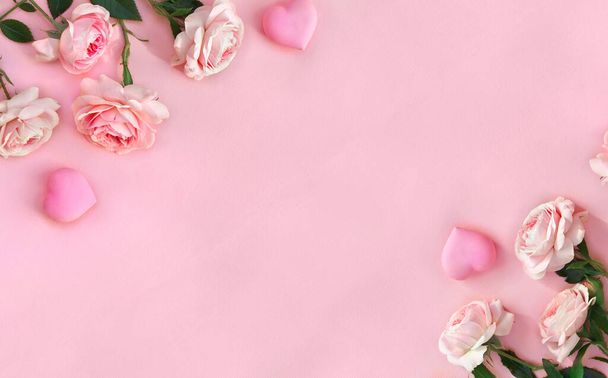 Blumengestell rosa Rosen mit Herzen auf rosa Papier Hintergrund mit Platz für Text. Dekoration zum Valentinstag. Draufsicht, flache Lage - Foto, Bild
