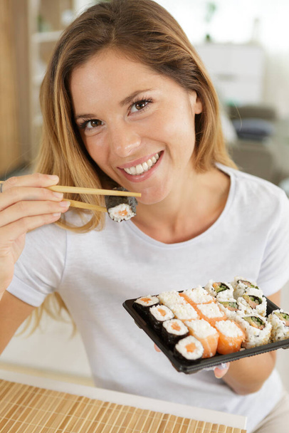 smiling young woman eating sushi - 写真・画像