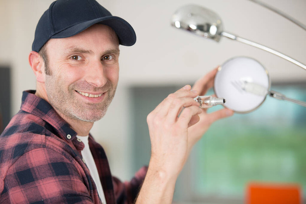 happy man changing light bulb in pendant lamp indoors - Zdjęcie, obraz