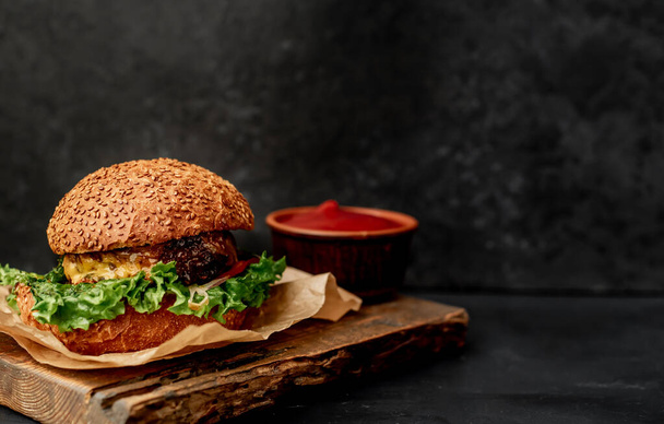 Fresh sandwich with meat, closeup of fried burger on black stone background - 写真・画像