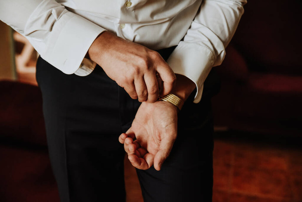 A closeup shot of a male in an elegant shirt adjusting his watch - Фото, зображення