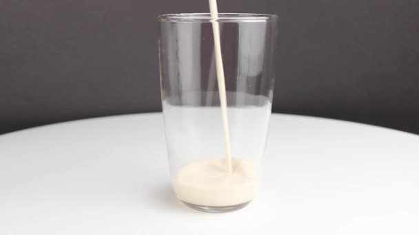 το ψημένο γάλα χύνεται σε ένα διαυγές ποτήρι. Κοντινό πλάνο, επιλεκτική εστίαση. - Πλάνα, βίντεο
