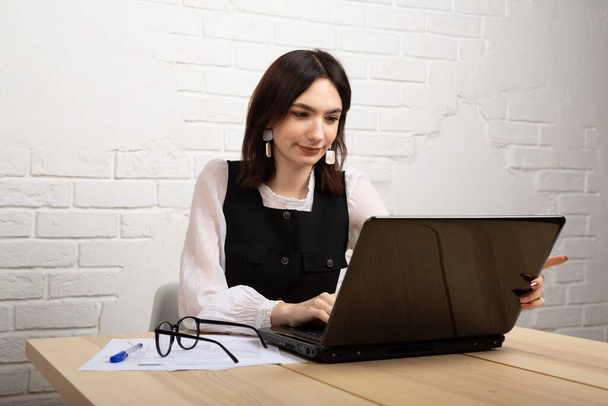 mooie jonge vrouw aan de tafel met laptop in het kantoor - Foto, afbeelding