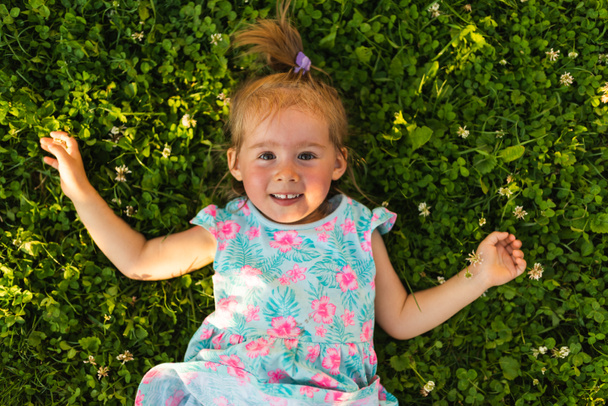 Giovane ragazza sdraiata sull'erba ridendo e guardando in alto. - Foto, immagini
