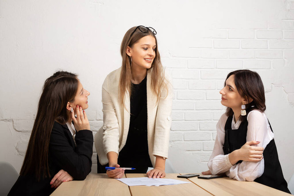 three beautiful young women with documents in the office - Foto, afbeelding