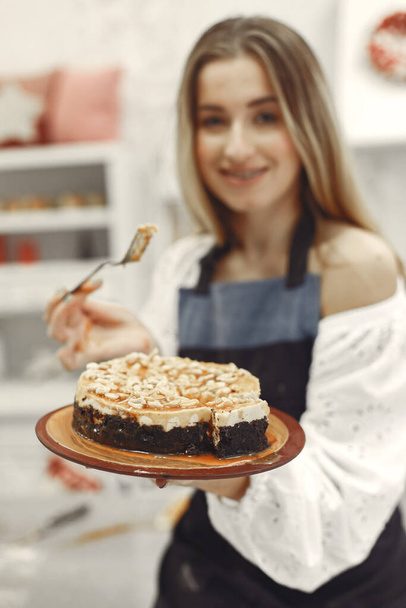 Young woman holding self-made cake in the kitchen - Фото, изображение