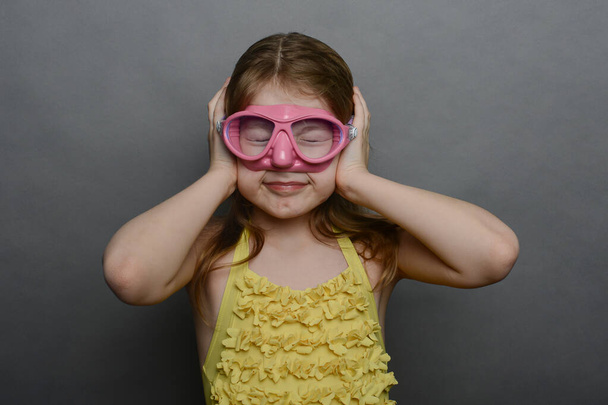 маленька дівчинка в жовтому купальнику і рожева маска
. - Фото, зображення