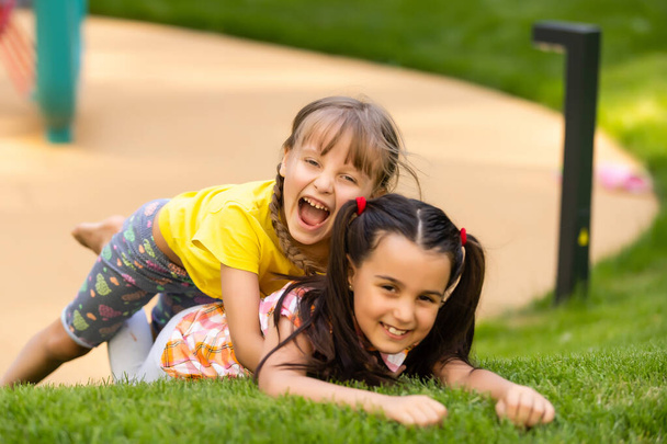 Portret van twee kleine meisjes die vechten in de achtertuin. Vrienden meisjes hebben plezier. Lifestyle openhartig familie moment van broers en zussen ruziën samen spelen. - Foto, afbeelding