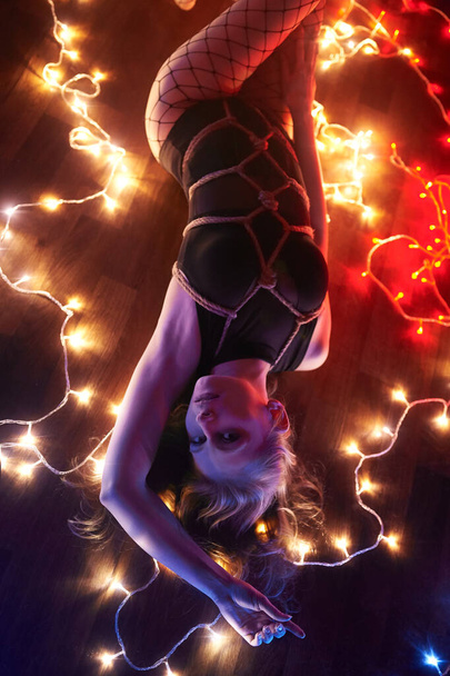 Shibari in the light of many lights. Domination over beautiful blonde - Фото, изображение