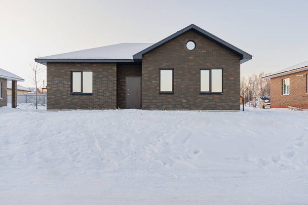 One-story brick house on the background of a snowy winter evening. Construction of low-rise buildings for further sale. Concept of building business. - Fotó, kép