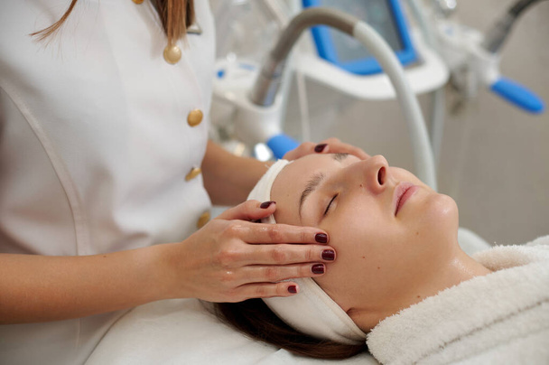 Docteur esthéticienne massages temple tête à un client heureux - Photo, image