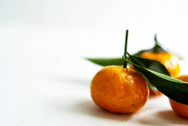 Three ripe tangerines with leaves close-up on a light background. Copy space. - Foto, afbeelding
