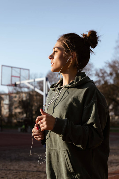 Athletic girl are running at stadium.Young women running during sunny morning on stadium track. Girl listens to music on headphones while running. Sport and healthy lifestyle. - Photo, image