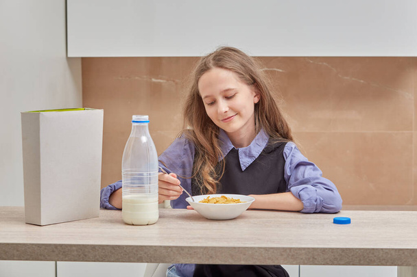 Cute blonde girl eating Breakfast in the morning before school. - Фото, зображення