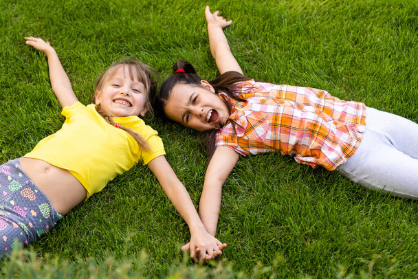 Portret van twee kleine meisjes die vechten in de achtertuin. Vrienden meisjes hebben plezier. Lifestyle openhartig familie moment van broers en zussen ruziën samen spelen. - Foto, afbeelding