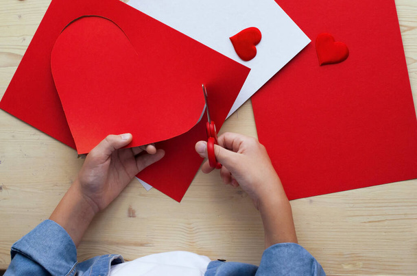  DIY prázdninová karta s červeným papírovým srdcem, symbol lásky. Dítě dělá Den matek, Valentýna, přání k narozeninám. Koníček, koncept dětského umění, dárek vlastníma rukama, DIY nápady pro děti - Fotografie, Obrázek