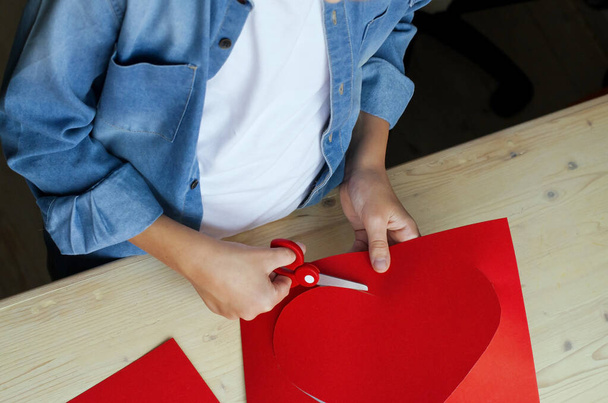  DIY holiday card with red paper heart, symbol of love. Kid makes Mother's Day, Valentine's Day, birthday greeting card. Hobby, children art concept, gift with your own hands, DIY Ideas for children - Photo, image