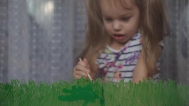 Infancia, creatividad, naturaleza, primavera, concepto de verano - primer plano de niña linda 3-4 años dibujar con colores acrílicos en vidrio de la ventana. paisaje de pintura infantil preescolar: sol, árbol, nube, lluvia, flor - Metraje, vídeo