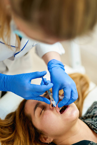 O médico cosmetologist faz Lip procedimento de aumento de uma mulher bonita em um salão de beleza - Foto, Imagem