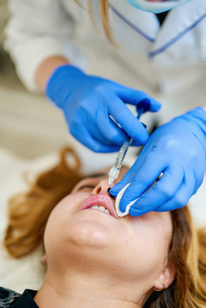 Жінка отримує ін'єкції краси для губ. Лікар-косметолог робить процедуру збільшення губ красивої жінки в салоні краси
 - Фото, зображення