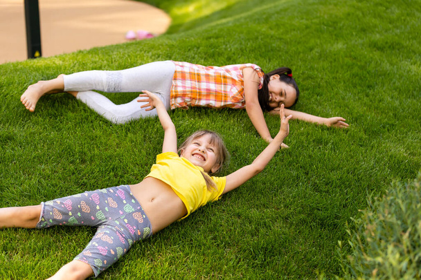 家の裏庭で戦っている2人の女の子の姉妹の肖像画。友達の女の子が楽しんでいる。一緒に遊んでいる兄弟のライフスタイル率直な家族の瞬間. - 写真・画像