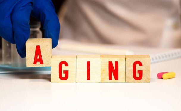 Aging - word from wooden blocks with letters, growing old senescence ageing concept, random letters around white background - Photo, Image