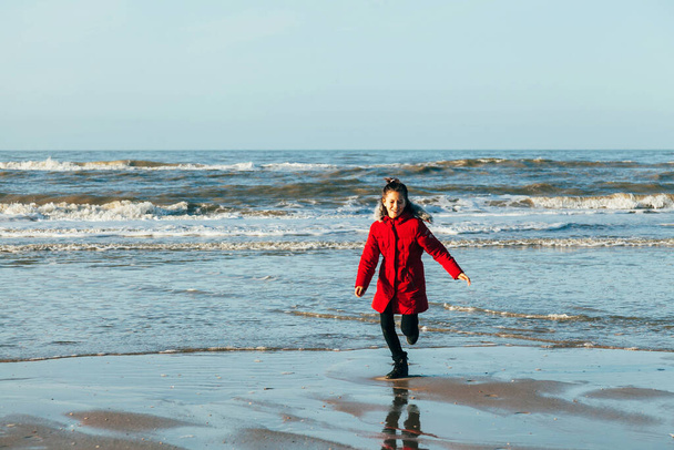 12 years old child having fun on the beach - Teenage kid playing during winter time outdoor - Photo, Image