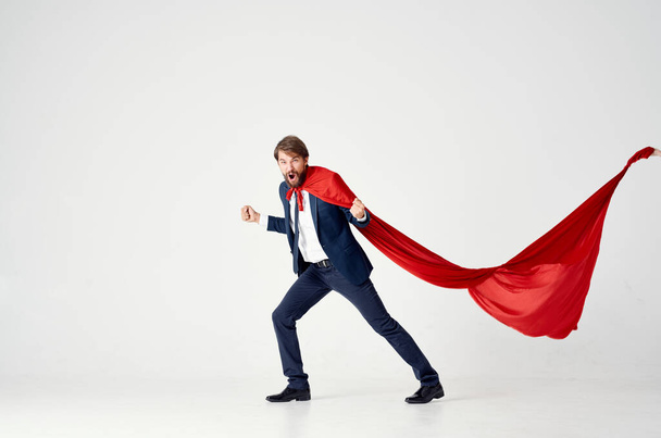 business man in a red cloak on a light background looks to the side success superhero suit - Photo, Image
