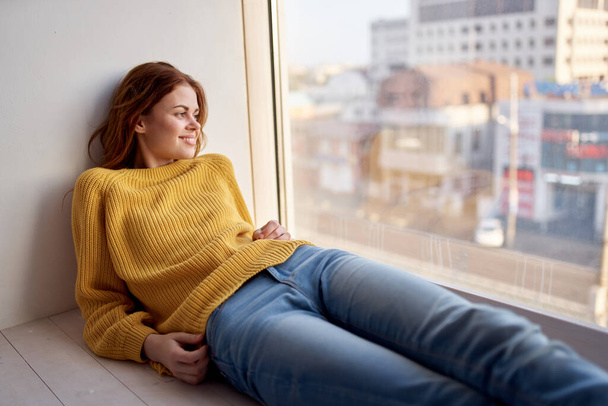 Nainen ikkunalaudalla keltaisessa puserossa ja farkuissa vapaa-ajan elämäntapa - Valokuva, kuva