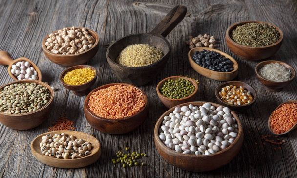 Vegan protein source.Various assortment of legumes, lentils, chickpea and beans assortment in different bowls on wooden table. Top view. - Photo, Image