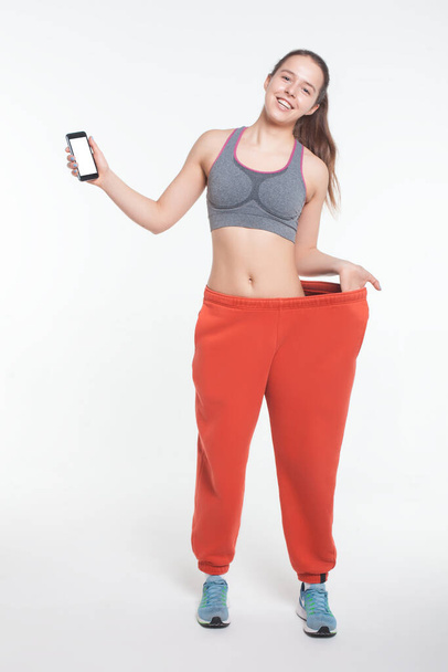 mladá žena po online hubnutí cvičení s chytrým telefonem izolované - Fotografie, Obrázek