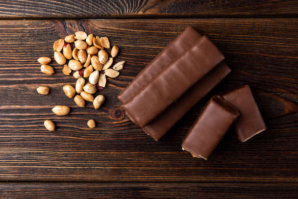 Csokoládé bár karamellás és mogyorós sötét fa háttér. - Fotó, kép