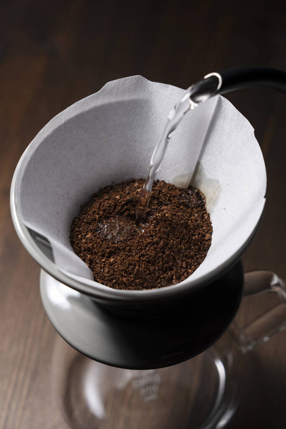 Das Kaffeepulver mit heißem Wasser übergießen - Foto, Bild