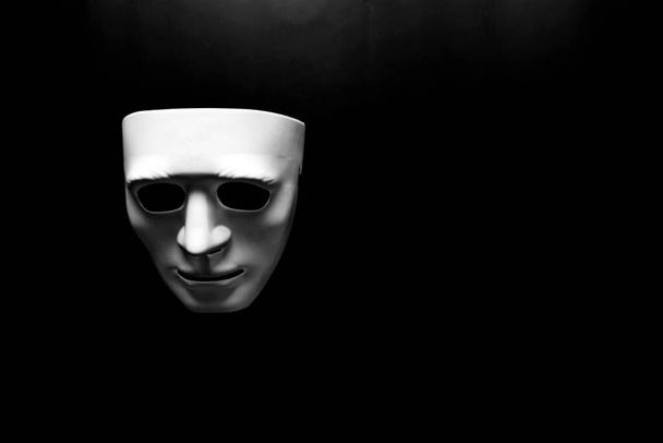Koyu arkaplandaki oyuncak yüz maskesinin sade ve seçici bir fotoğrafı. Depresyon ve psikolojik sorunlar kavramı. - Fotoğraf, Görsel