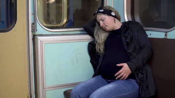Uma mulher grávida adormeceu num comboio do metro. Carro velho do trem do metrô
 - Foto, Imagem