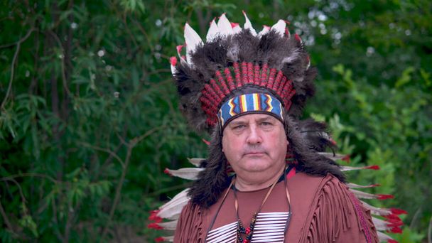 Стародавні індіанці Америки стоять на тлі лісу з серйозним обличчям. - Фото, зображення