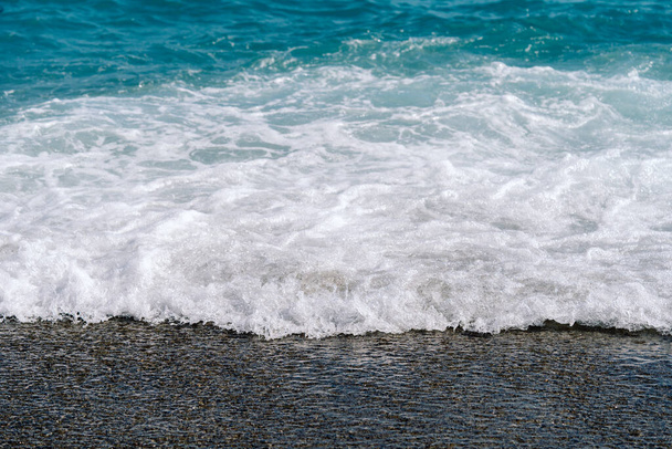 White foamy waves on sandy beach closeup. Seaside on sunny summer day. - Foto, imagen