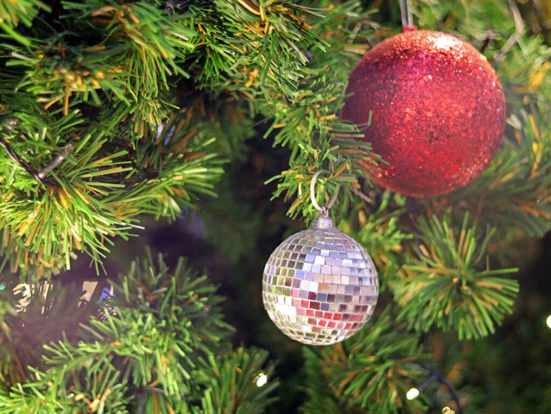 Kerstboom spar close-up decoratie met grote zilveren spiegel en rode glitter bal heeft wazig bokeh licht achtergrond selectieve focus, heeft kopieerruimte voor Kerstmis seizoen, uitnodiging kaart achtergrond. - Foto, afbeelding