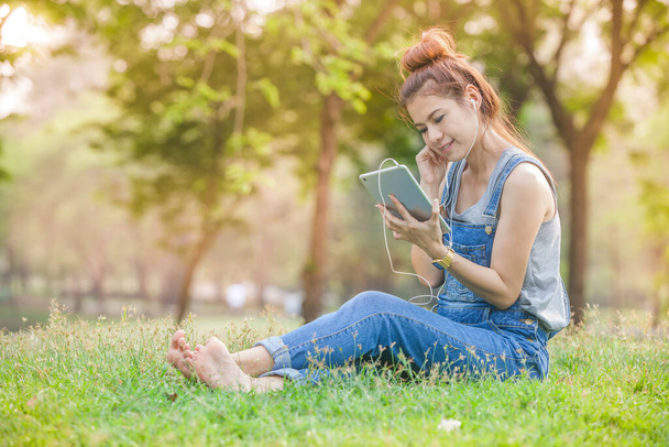 Woman using tablet outdoor with earphones - Fotó, kép