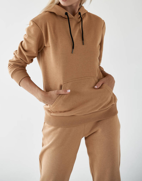 girl wears light brown hoodie and pants. isolated photo of women wearing nude color fleece textile outfit. - Photo, Image