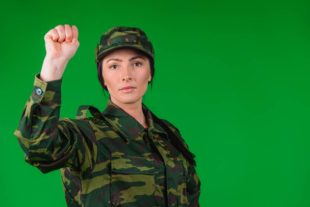 Handsome women in military uniforms show fist to the camera. Empty side space and green background. High quality photo - Fotografie, Obrázek