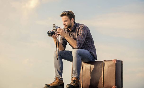 Get out there. macho man with camera on baggage. photographer in glasses. capture adventure. journalist. sexy man touristic reporter. traveler wait for car. male fashion style. looking trendy - Фото, изображение