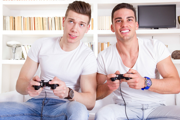 dos amigos masculinos jugando videojuego con controladores
 - Foto, Imagen