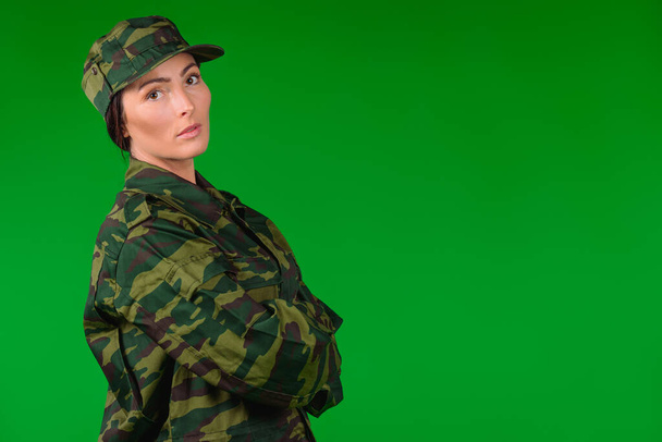 Serious woman in military uniform looks at the camera. Green background and empty side ad space. High quality photo - Foto, Imagem