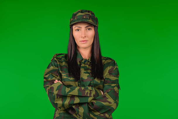 Portrait of a woman in military uniform with crossed arms on green background with empty side space. High quality photo - Photo, Image