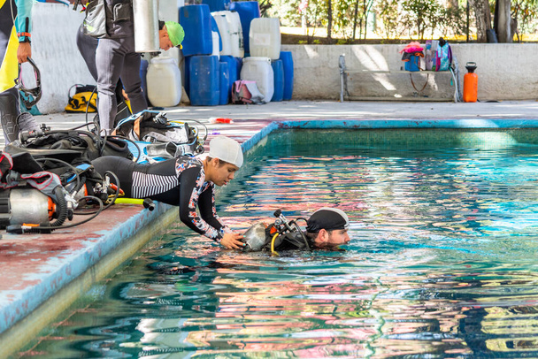 instruktor nurkowania pomaga praktykantowi ze zbiornikiem tlenu w wodzie - Zdjęcie, obraz