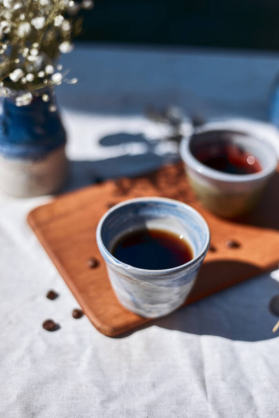 A cup of aromatic black coffee and coffee beans on the table. - Fotoğraf, Görsel