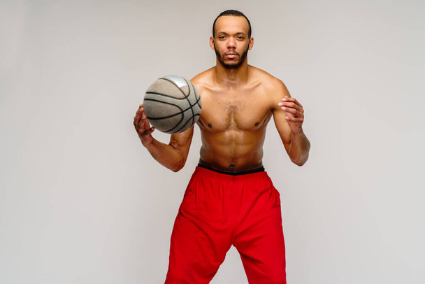Muscular african american sportsman playing basketball shitless over light grey background - Photo, Image